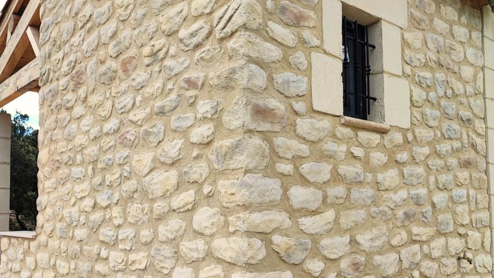 Façade extérieure en imitation pierre avec fenêtre à barreaux noirs