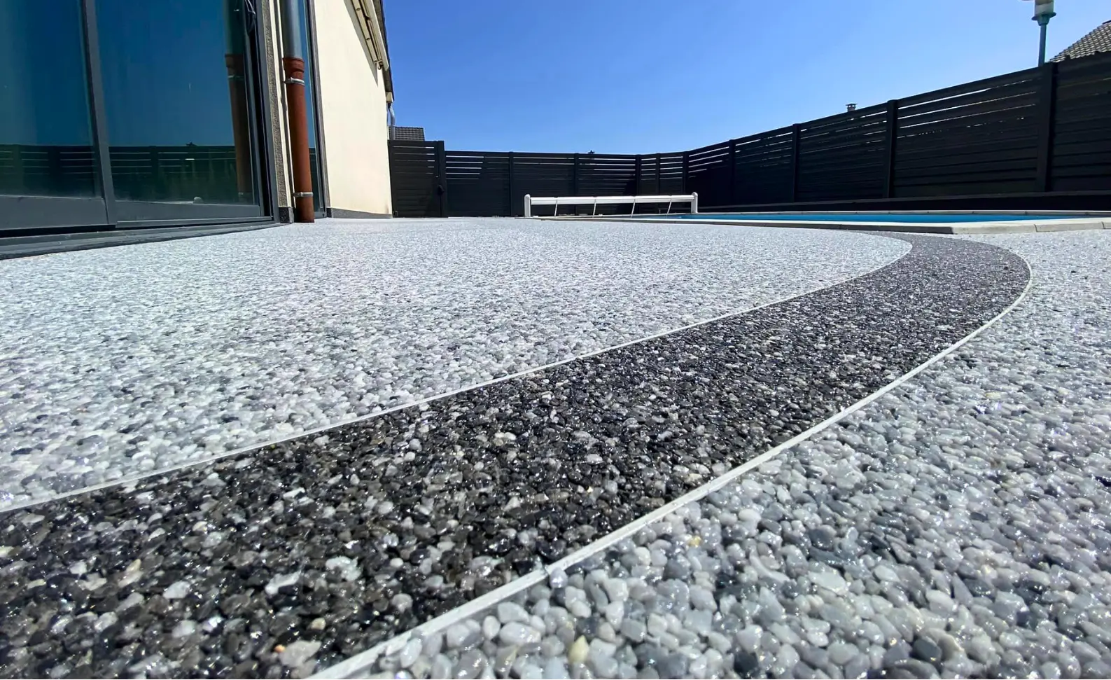 Terrasse en moquette de pierre grise et noire avec contour de piscine